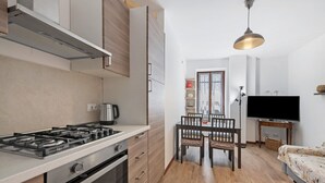 Eine moderne Küche mit Gasherd, Backofen und einem Essbereich mit Tisch und Stühlen.