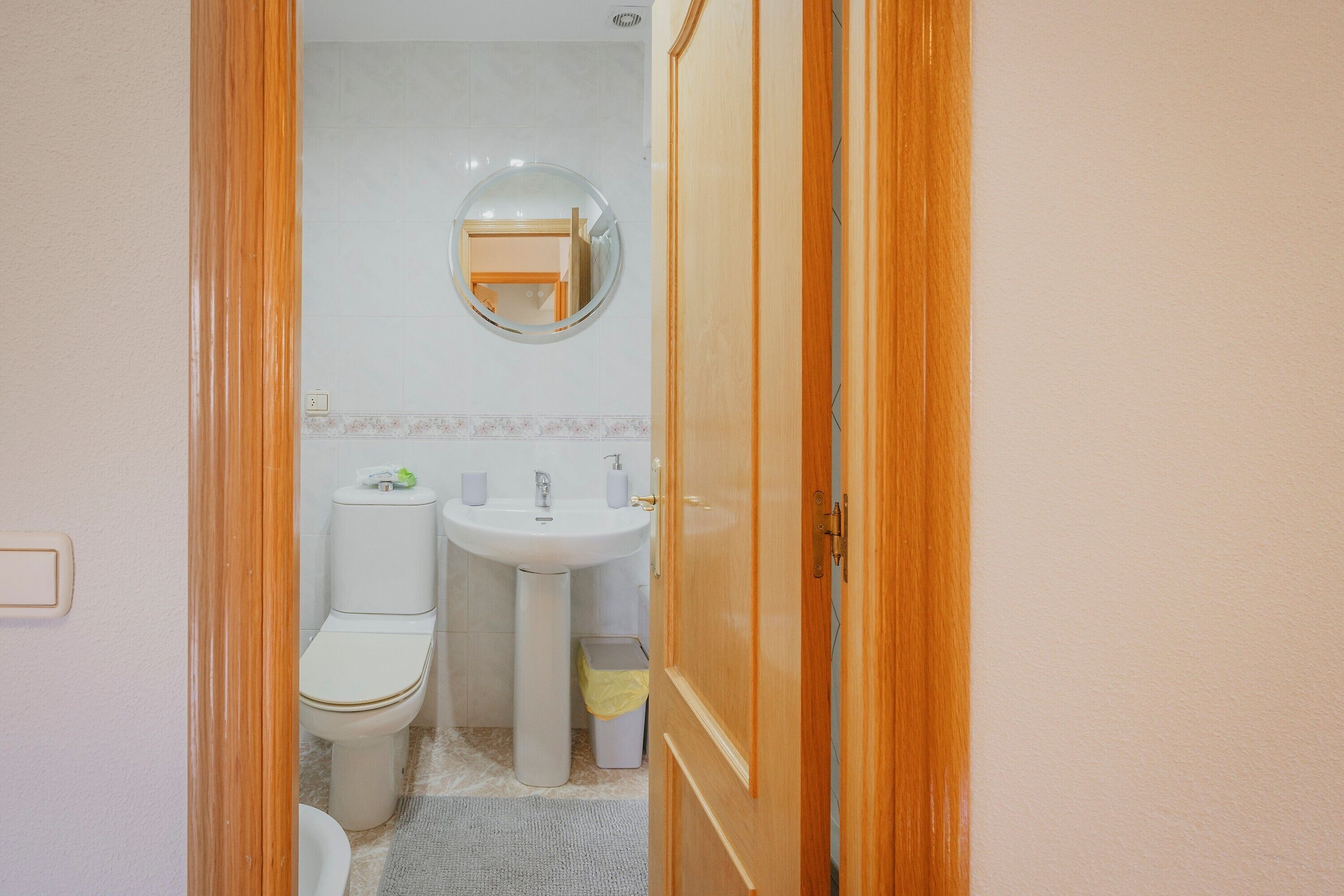 Une salle de bain équipée de toilettes, d’un lavabo, d’un miroir et d’une porte en bois.