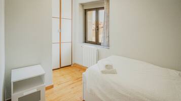 Une chambre à coucher avec un lit, une table de chevet, une fenêtre et un radiateur.