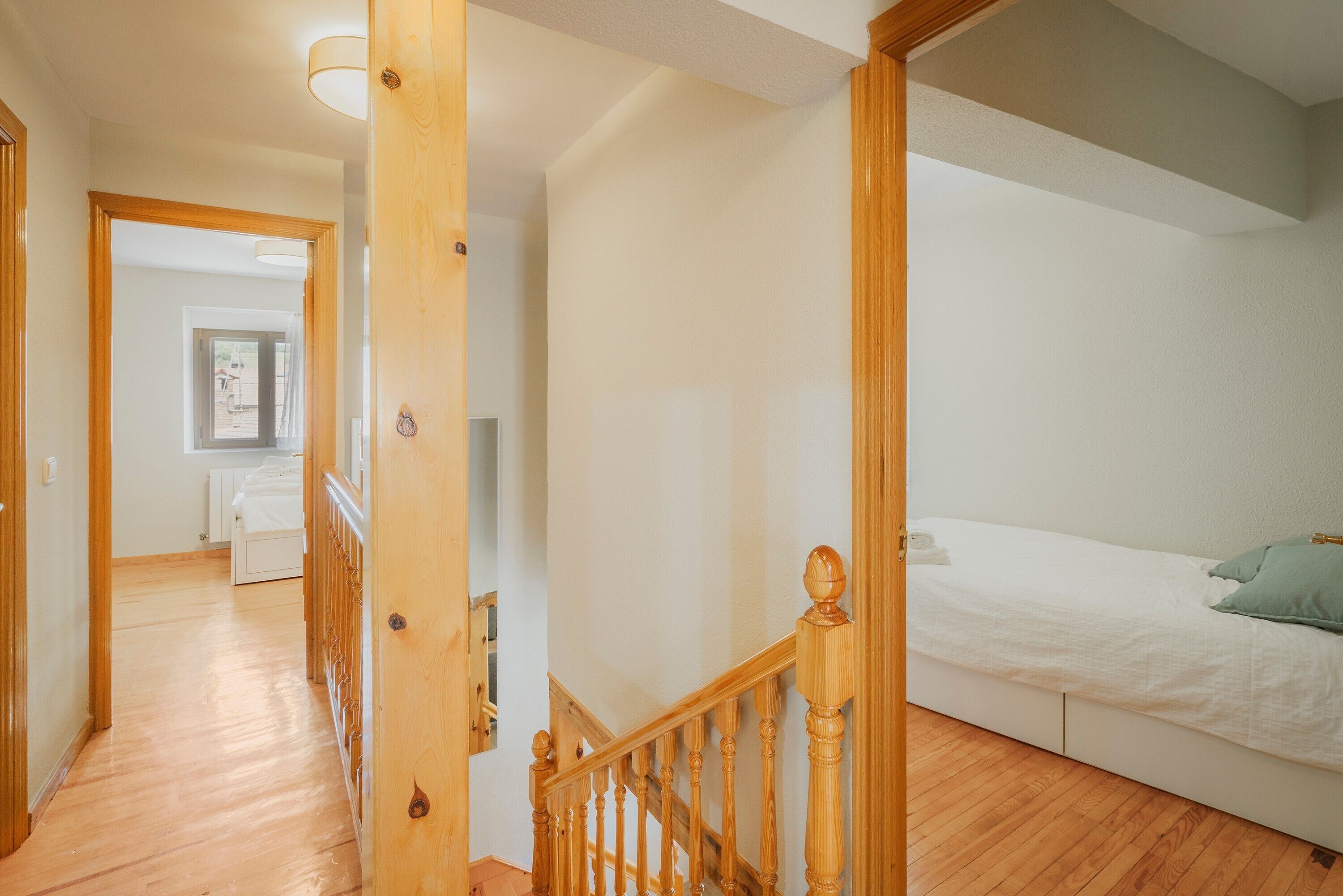 Une chambre avec un escalier en bois, un lit et un couloir menant à une autre pièce.