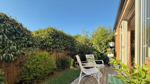 A wooden deck with two white wicker chairs, a small table, and a potted plant. - Soft Modern Glamour in the Heart of Camberwell (Camberwell)