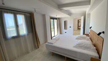 Quarto moderno com uma cama grande, uma porta de correr de vidro para uma varanda e vista para o exterior.
