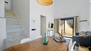 A modern interior with a wooden dining table, a vase, and a staircase.