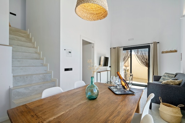 A modern interior with a wooden dining table, a vase, and a staircase.