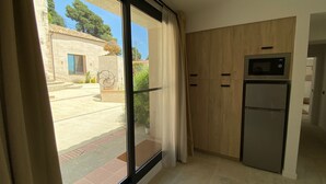 A kitchen with a built-in microwave, a refrigerator, and a sliding glass door leading to a courtyard.