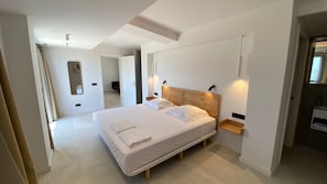 A modern bedroom with a large bed, bedside tables, a mirror, and a walk-in closet.