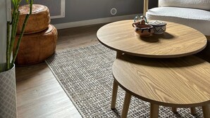 A modern living room with a large window, a round wooden table, a white armchair, and a potted plant. - Spa suite, bohemian ambience & romantic experience (Saumur)