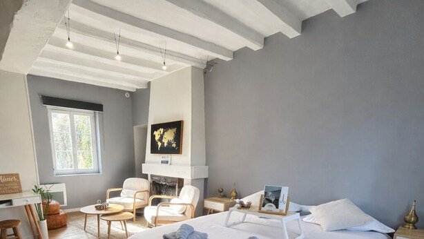 A modern bedroom with a large bed, a desk, a chair, and a fireplace. - Spa suite, bohemian ambience & romantic experience (Saumur)