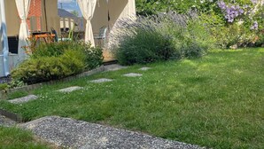 A garden with a white tent, a brick wall, and various plants. - Spa suite, bohemian ambience & romantic experience (Saumur)