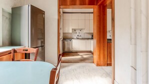 A compact kitchen with a refrigerator, dishwasher, and wooden cabinets.