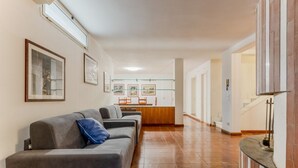 A hallway with a sofa, framed pictures, and a kitchen area.