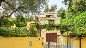A yellow building with a gated entrance, surrounded by greenery and trees. - Holiday Home 'L'ulivo' a few steps from the sea with Garden View, Wi-Fi and Air Conditioning (Torre Delle Stelle)