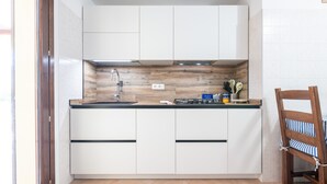 A compact kitchen with white cabinets, a wooden backsplash, and a black countertop. - Holiday Home 'L'ulivo' a few steps from the sea with Garden View, Wi-Fi and Air Conditioning (Torre Delle Stelle)