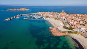 An aerial view of a coastal town with a marina, buildings, and a prominent tower.