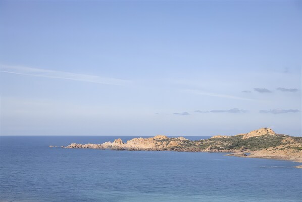 Un paisaje costero con un promontorio rocoso y mar en calma.