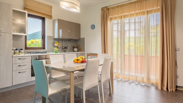 Une cuisine moderne avec un coin repas, comprenant une table avec des chaises, une cuisinière et une fenêtre avec des rideaux.