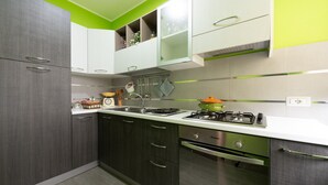 A modern kitchen with grey cabinets, a white countertop, and a green accent wall. - Apartment 'Luna Piena' with Sea View, Wi-Fi and Air Conditioning (Tusa)
