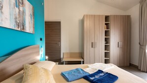 A hotel room with a bed, a wardrobe, a small table, and a painting on the wall. - Apartment 'Luna Piena' with Sea View, Wi-Fi and Air Conditioning (Tusa)