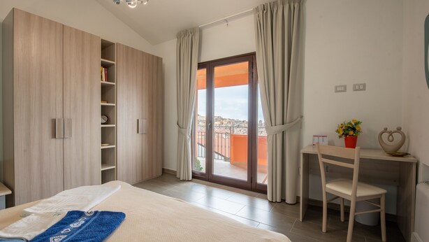 A bedroom with a bed, a desk, a chair, a wardrobe, and a sliding glass door to the outside. - Apartment 'Luna Piena' with Sea View, Wi-Fi and Air Conditioning (Tusa)