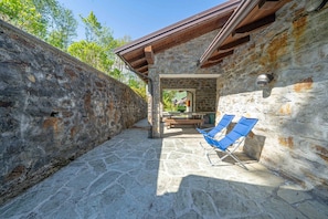 A stone patio with a wooden ceiling and a stone wall.