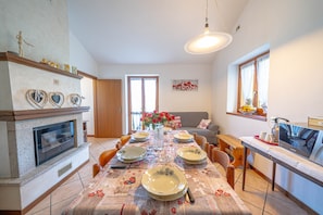 A dining area with a table set for four, a fireplace, and a television on a stand.
