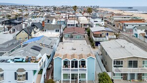 Un quartier résidentiel situé sur la côte, avec une maison remarquable dotée d’un balcon, d’une terrasse avec mobilier d’extérieur et d’une vue sur la plage.