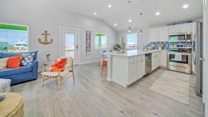 A modern kitchen with white cabinets, a stainless steel refrigerator, and a built-in oven. - Sleeps 21, 2 Homes | Private Pool, Covered Patio Lounge, Bar, TV, & Games (Port Aransas)