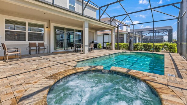A swimming pool with a hot tub, outdoor seating, and a covered patio area. - Pool, Hot Tub+Game Rm, Mins to Disney & Universal | Sunshine Ridge by AvantStay (Kissimmee)