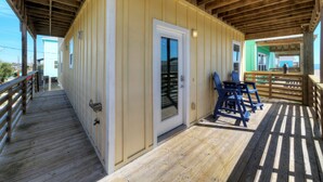 Une terrasse en bois avec une porte donnant sur une pièce, une chaise et une petite table.