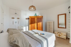 A bedroom with a bed, wardrobe, dresser, and a mirror.