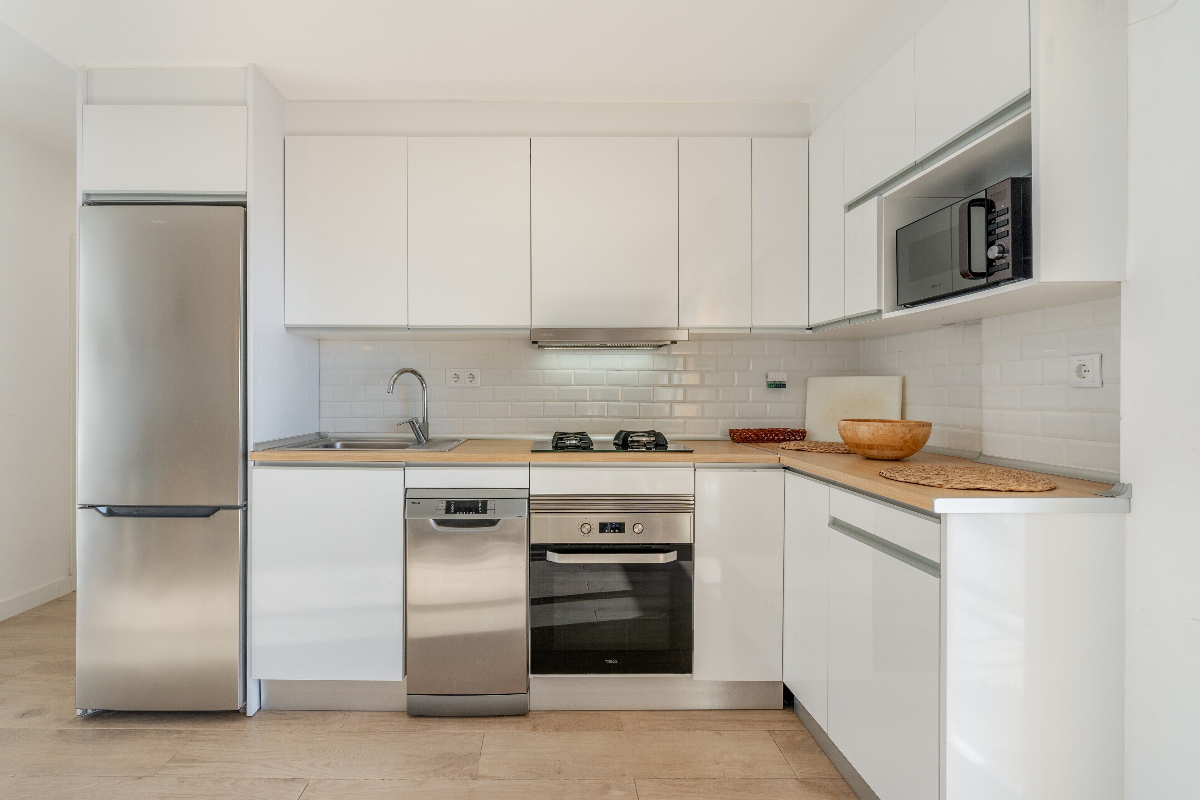 Eine moderne Küche mit weißen Schränken, Edelstahlgeräten und einer Holz Arbeitsplatte.