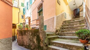 Eine schmale Gasse mit Steinstufen, die zu einem Hauseingang führen, umgeben von bunten Gebäuden.