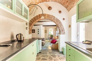 Una cocina con armarios verdes, piso de piedra y techo de ladrillo en arco.
