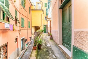 A narrow alleyway with buildings on either side, a small staircase, and potted plants. - Charming 50 sqm apartment in the center of Riomaggiore, with a large equipped terrace. It is located on the second floor of a 2-storey building (10 steps to access, NO elevator).The apartment is located in a central area, close to all services, the sea a (Riomaggiore)