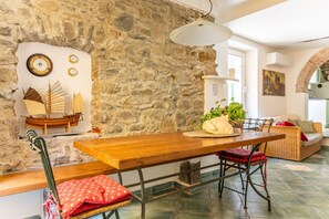 A rustic interior with a stone wall, wooden table, and a ship model. - Charming 50 sqm apartment in the center of Riomaggiore, with a large equipped terrace. It is located on the second floor of a 2-storey building (10 steps to access, NO elevator).The apartment is located in a central area, close to all services, the sea a (Riomaggiore)