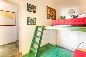 A room with a bunk bed, a ladder, a map on the wall, and colorful artwork.