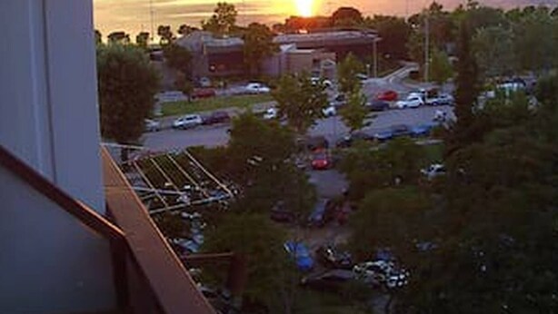 Une vue d’un coucher de soleil sur une étendue d’eau, avec un parking et des bâtiments au premier plan.