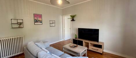 A living room with a sofa, TV, wooden coffee table, and a hanging light fixture.