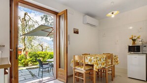 A kitchen with a dining table, chairs, a refrigerator, and an air conditioning unit. - Apartment 'Panorama' with Lake View, Wi-Fi and Air Conditioning (Brenzone sul Garda)