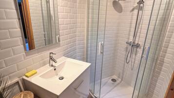 Une salle de bain moderne avec une douche à parois de verre, un lavabo blanc et un meuble-lavabo en bois.