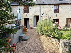 A stone building with a gravel courtyard, outdoor seating, and potted plants.