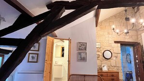 A rustic room with exposed wooden beams, a stone wall, a wicker chair, a dresser, and a mirror. - Abbaye Cottage
Charming House in the Heart of Fontevraud-Private Garden-Jacuzzi (Fontevraud-l'Abbaye)