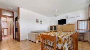 Una habitación con una mesa de comedor, sofá, televisor y armarios.