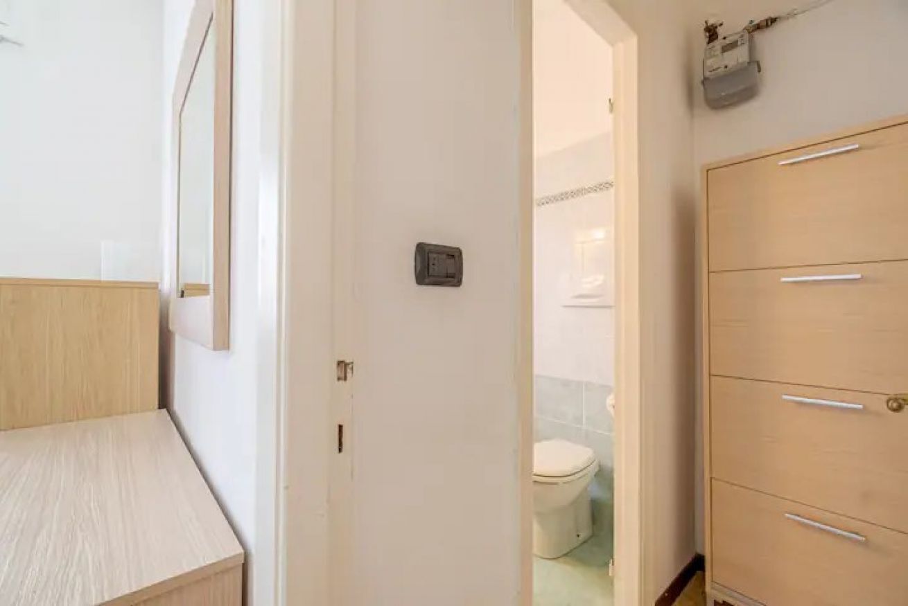 A bathroom with a toilet, a cabinet with drawers, and a mirror on the wall.