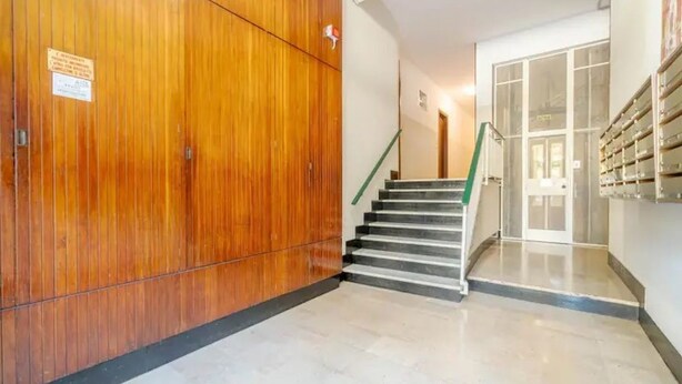 Un couloir avec un mur en bois, un escalier et une porte en verre.
