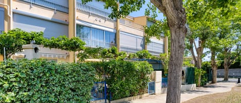 Un edifici amb un balcó, un arbre i una tanca.
