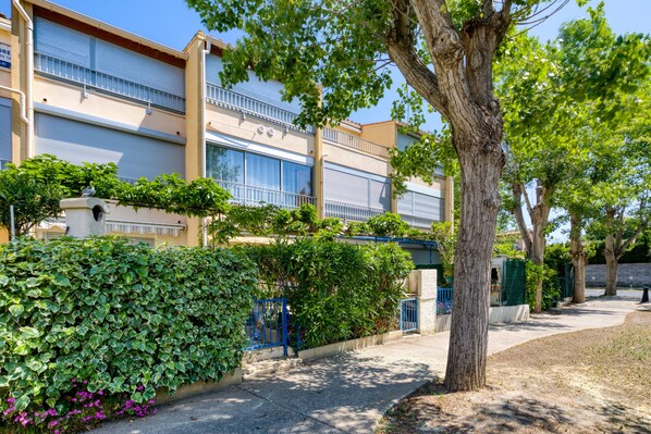 A building with a balcony, a tree, and a hedge.