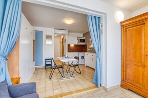 A compact living space with a kitchenette, dining area, and a wardrobe.