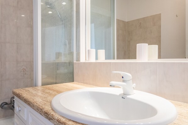 A bathroom with a white sink, a mirror, and a shower area.