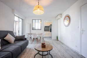 A modern living room with a sofa, a dining table, and a kitchen in the background. - Cocooning – Your Peaceful Haven Just 10 Minutes’ Walk from Fréjus Beaches (Fréjus)